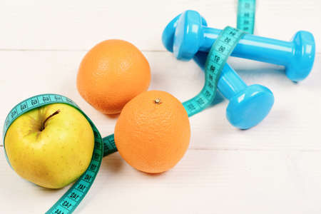sport concept, dumbbells weight with measuring tape, orange and appleの写真素材