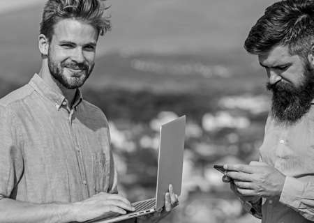 Mobile internet concept. Colleagues with laptop work outdoor sunny day nature background. Business...