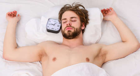 Picture showing young man stretching in bed. Close up of feet in a bed under white blanket. Man morning bed.の写真素材