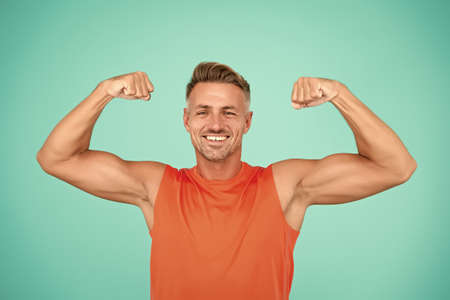 Stay strong in your life. Happy athlete show physical strength. Strong man flex arms blue background. Building strong biceps and triceps. Strong muscle workout. Sport and fitness. Get strongerの写真素材