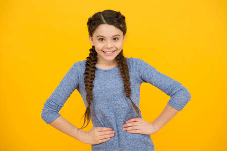 happy child girl has fashionable hairstyle on yellow background, hairdresser