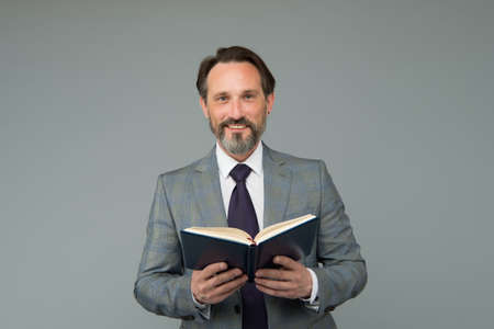 Happy school teacher in formal suit hold open book teaching lesson grey background, literatureの写真素材