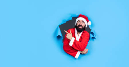 happy bearded man in santa claus costume celebrate new year winter holiday pointing finger on copy...