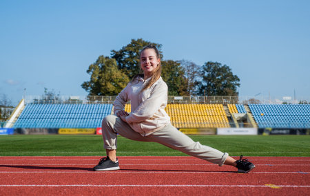runner prepare for race competition. sprinter warming up on stadium gym. flexibility. child training at school physical education lesson. teenage girl stretching before run. Staying fit and healthyの写真素材
