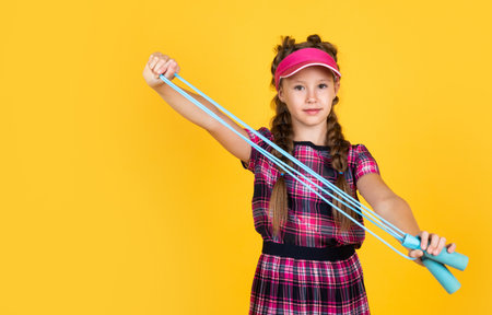 happy girl holding sport equipment. kid hold tennis racket. child wear ftness cap. childhood activity. healthy way of life. be energeticの写真素材