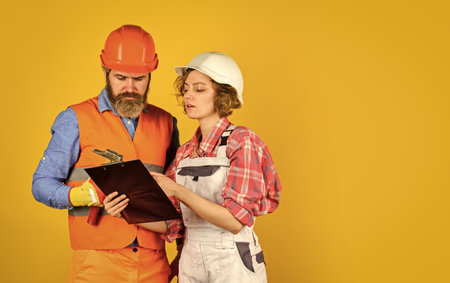 Family counting finances for renovation. Woman and man wear safety hard hat. Redevelopment of home....