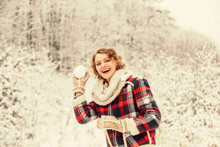 Winter holidays. happy woman enjoy winter landscape. woman warm clothes in snowy forest. trees covered white snow. female casual style for cold season. girl make and play snowball. winter activityの写真素材
