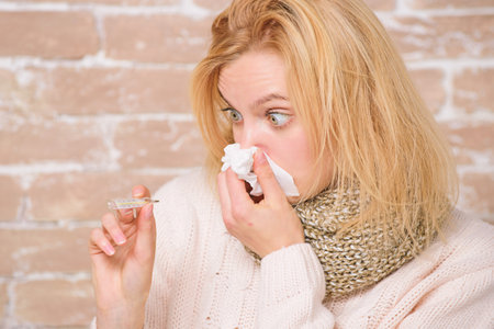 Continuous fever. Cute ill girl measuring body temperature. Unhealthy pretty woman suffering from...