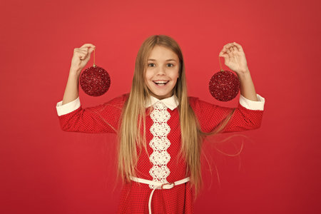 too much fun. ready for new year celebration. Festive mood. Create unique decorations. small girl red wall. elf kid decorative tree ball. feeling happy about xmas holiday. christmas shopping timeの写真素材