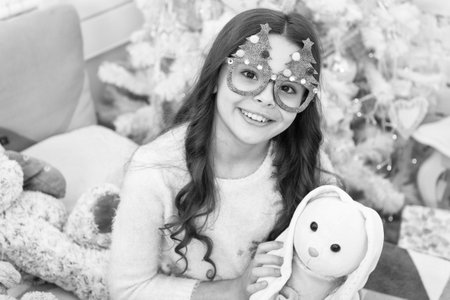 Winter holidays. Kid relaxing. Adorable little girl wear christmas tree glasses photo booth props. Rest and relax. Christmas eve. Small girl at home christmas vacation. Carefree childhood. Good vibesの写真素材