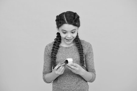 Define Beauty. female beauty and fashion. small girl apply powder with makeup brush. put blush on. surprised child has hair braids. natural cosmetics for kids. happy little girl create her imageの写真素材