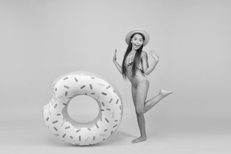 Safety on water. Safety measures around pool to keep bathers safe. Little girl and swimming donut ring. Kid in swimsuit having fun. Summer vacation. Swimming and sunbathing. Accessories for swimmingの写真素材
