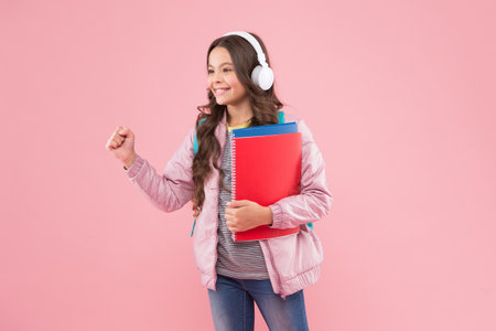 Happy energetic school kid listen to music record playing in headphones pink background, solfeggioの写真素材