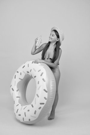 People skin protection. childhood happiness. child healthcare. small beauty. happy kid with rubber ring. summer vacation activity. cheerful little girl wear swimsuit and straw hat. pool and beach funの写真素材