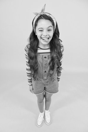 Fun lifestyle little girl long hair denim overalls, cheerful grimace concept