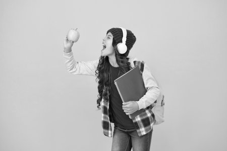 Yum yum. Happy kid bite green apple. Little girl enjoy school snack. Food and health. Healthy eating and dieting. Child health and care. Health and education. For the health benefitsの写真素材