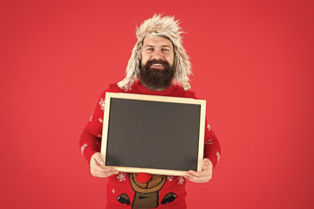 Ad man. Happy man hold empty blackboard. Bearded man in winter wear. Hipster with mustache smile. Brutal man with advertising board, copy spaceの写真素材