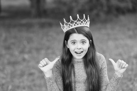 My beauty deserves crown. Emotional child give thumbs ups. Little miss wear crown. Beauty pageant. Party crown. Fashion accessory. Luxury diadem or tiara. Big boss. Hair salon. Always wear your crownの写真素材