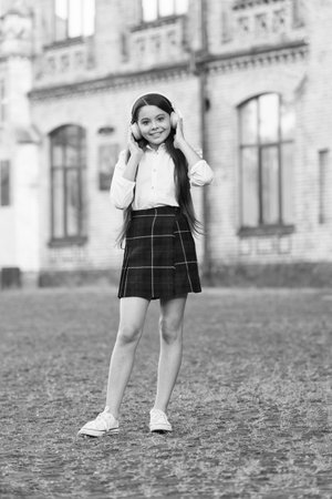 Sound learning. Happy child listen to sound file in headphones. Small girl enjoy music outdoors. Music school. Hi-Fi stereo sound. Sound technology. Listening comprehension. Modern lifeの写真素材