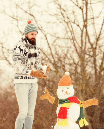 Winter flu. winter holiday outdoor. warm sweater in cold weather. man play with snow. winter season activity. its christmas. bearded man build snowman. happy hipster ready to celebrate xmasの写真素材
