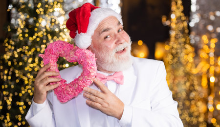 Charity and kindness. Christmas eve. Lovely greetings. Senior man celebrate christmas. Santa Claus. Kind grandpa with heart. Christmas decoration. Love and care. Mature man with white beardの写真素材