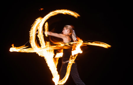 Sexy woman performer create beautiful fire patterns dark outdoors, beautyの写真素材