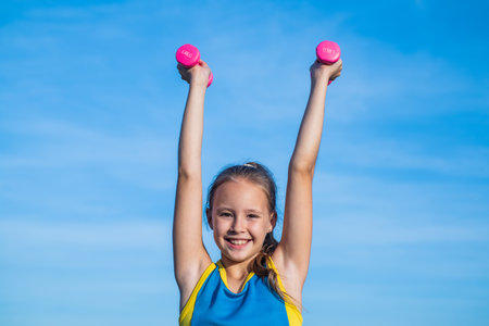 aim and success. healthy child training with barbells. fitness kid hold dumbbell. weight lifting. teenage girl do exercise. happy childhood. future of sport. warm up for workout in morningの写真素材