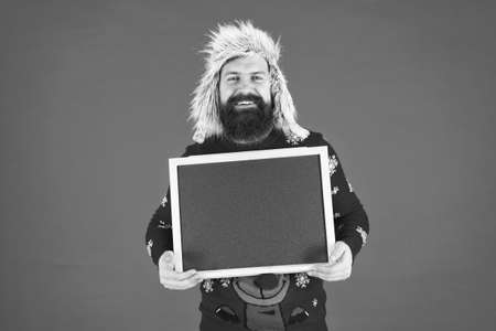 Happy man hold empty blackboard. Bearded man in winter wear. Hipster with mustache smile. Brutal man with advertising board, copy spaceの写真素材