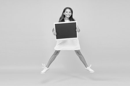 This is the life. summer vacation and holiday. happy childhood. jumping small girl hold blackboard.の写真素材