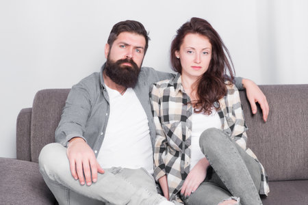 Regular couple relaxing on couch. Session at family psychotherapist. Couple in love hug looking at camera. Family relations. Family leisure. Happy and healthy relations. Bearded man and pretty girlの写真素材