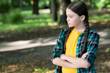 Adorable girl child with long hair in casual fashion style keep arms crossed natural summer landscape, look, copy spaceの写真素材
