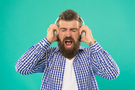mature male hipster enjoy music in headset on blue background, modern device