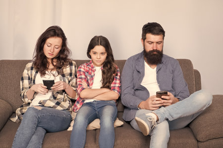 Ignored child. Busy parents surfing internet smartphones. Dad and mom ignoring daughter needs. Bad habits. Parenthood failure. Ignored baby. Offended feelings. Stop ignoring kid. Stuck in onlineの写真素材