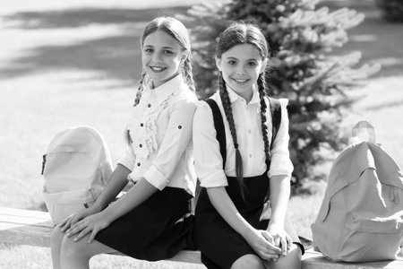 Exams. happy childrens day. childhood hapiness. two sisters in school uniform outdoor. ready for holidays. happy teen kids carry backpack. back to school. small school girls walking in springの写真素材
