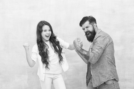 Shes champion. Happy child overcome father in arm wrestling. Girl child won competition. Celebrating...