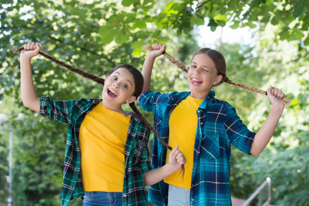 Interested in my hair and my hairdresser. Happy girls hold long pigtails summer outdoors. Hairdressing salon for children. Beauty parlor. Hair stylist and hairdresser. Hairstyling and haircareの写真素材