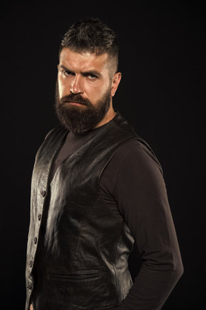 Man confident and brutal style black background. Barbershop concept. Grow mustache. Fashion model. Strict mature face. Facial hair. Male face. Handsome face. Man with beard in black leather clothesの写真素材