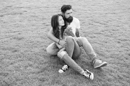 Turning family vacation into honeymoon. Couple in love sit on green grass. Summer vacation. Enjoying...