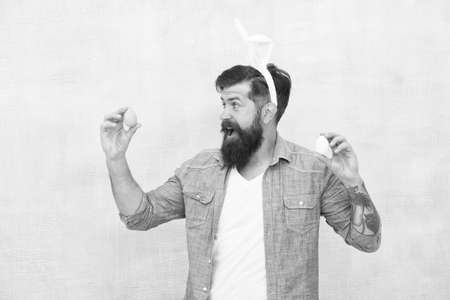 Man in bunny ears holds egg. Spring time. Easter eggs. Happy Easter. Being prolific. Celebration of...