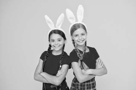 Entertainment and event concept. Spring holidays. Children in rabbit bunny ears. Family and sisterhood. Little schoolgirls same school uniform with long bunny ears. Happy Easterの写真素材