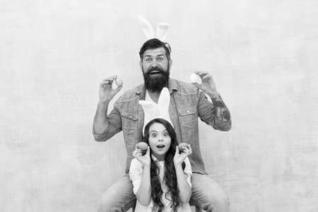 Spring mood. easter family party. happy easter concept. father and daughter collect pained eggs. egg hunt is right now. having fun in rabbit costume. dad and child wear bunny earsの写真素材