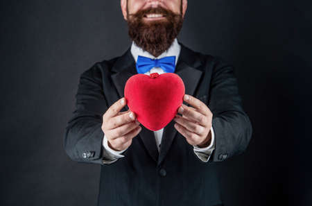 heart in hands of happy tuxedo man. happy valentines day. be my valentine. love and romance.の写真素材