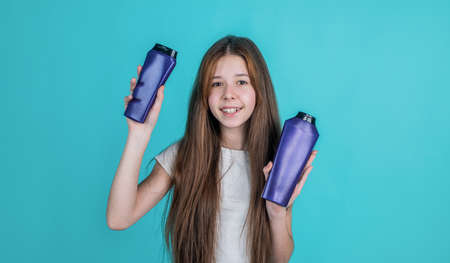 Making hair look magical. beauty. wash and rinse. happy teen girl presenting cosmetic product. shampooing hair in salon. daily habits and personal care. child use shampoo in bottle. hair conditionerの写真素材