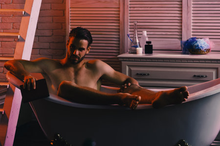 Sex and relaxation concept: guy with book in bathtub