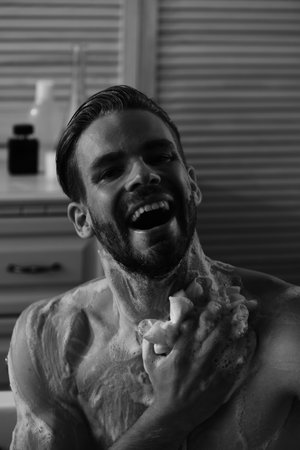 Relaxation and erotica concept: naked macho washing in bathtub