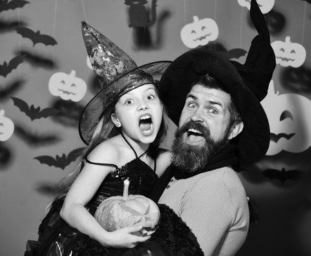 Wizard and little witch in black hats hold pumpkinの写真素材