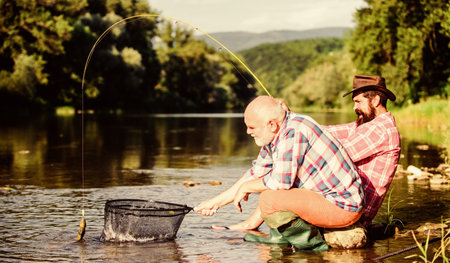 Gone Fishing. big game fishing. relax on nature. Two male friends fishing together. fly fish hobby of men. retirement fishery. happy fishermen friendship. retired father and mature bearded sonの写真素材