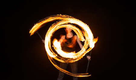 female fire dancer twirl burning baton creating sparkling trails in motion dark outdoors, twirlerの写真素材