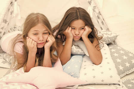 Bored kids on quarantine. Sisters best friends spend time together lay on pillows. Girls feeling...