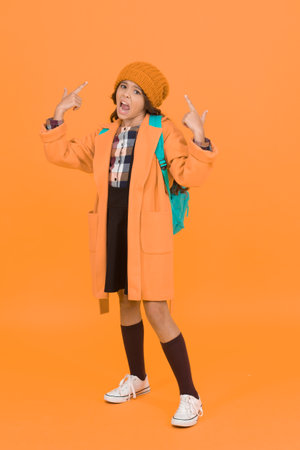 Listen to me. Unhappy small child hand gesturing on yellow background. Small schoolchild on autumn day. Small girl back to school. Adorable small child in autumn fashionの写真素材